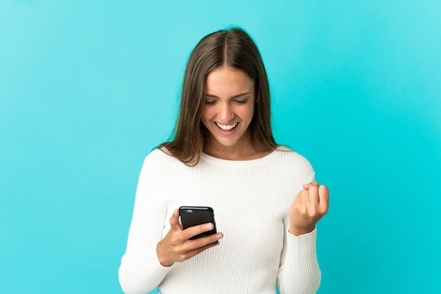 Jeune femme sur fond bleu isolé surpris et envoyer un message