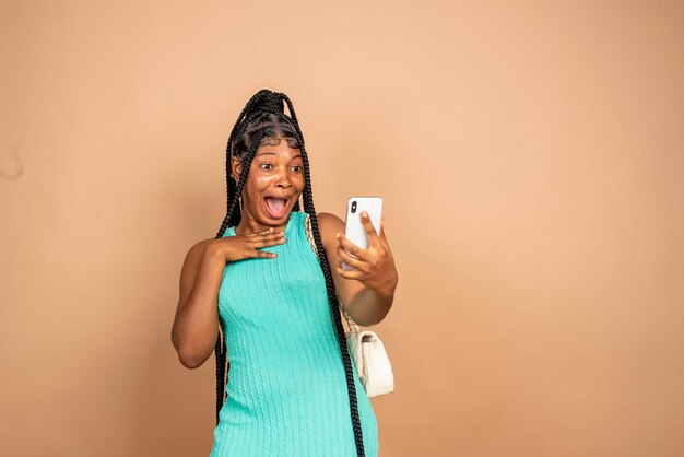 Photo une jeune femme sur un fond plat isolé avec un téléphone en position de victoire