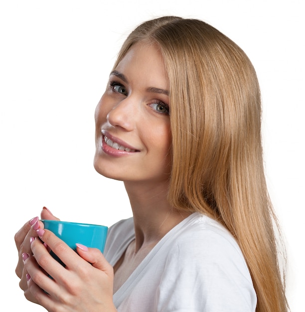 Jeune femme sur fond de studio boit du café ou du thé