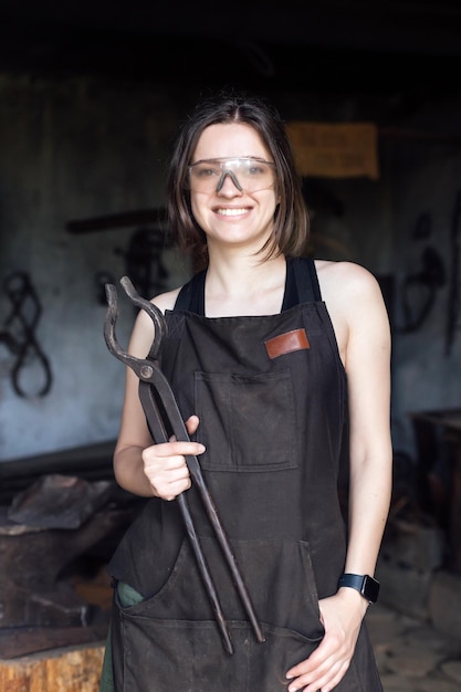 Jeune femme forgeron portraitin lunettes de protection en atelier