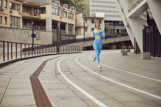 Une jeune femme en forme fait du fitness et du jogging dans un lieu urbain