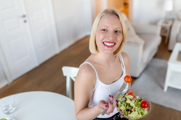 Jeune femme en forme mangeant une salade saine après l'entraînement Fitness et concept de mode de vie sain jeune femme en bonne santé mangeant de la salade verte