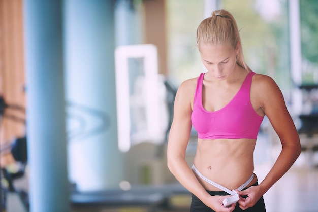 jeune femme en forme mesurant le ventre lors d'une formation en salle de fitness