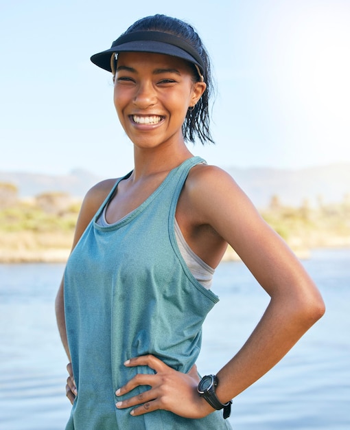 Jeune femme en forme profitant de son temps libre en vacances ou en week-end à l'extérieur sur un lac ou une rivière Athlétique souriante femme debout à l'extérieur avec ses mains sur ses hanches par une journée ensoleillée