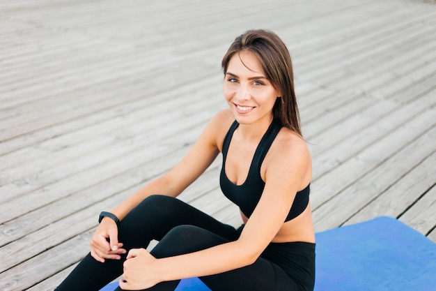 Jeune femme en forme de repos assis sur un tapis