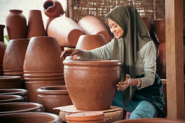 Jeune femme en foulard assis entre des pots de poterie