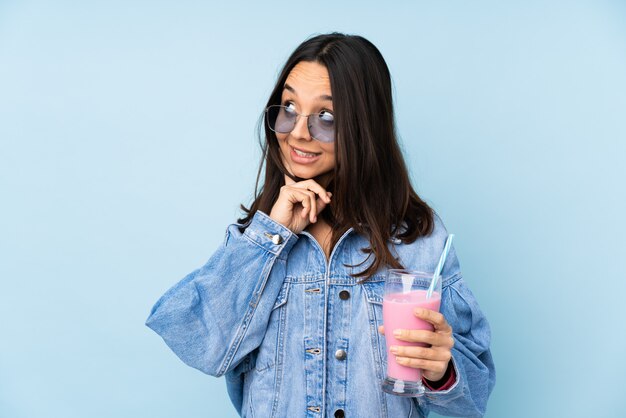 Jeune, femme, fraise, milk-shake, isolé, bleu, mur, pensée, idée, quoique, recherche