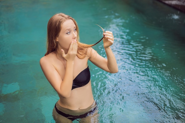 Jeune femme frustrée ayant de mauvais cheveux dans la piscine en raison du fait que des produits chimiques dans la piscine