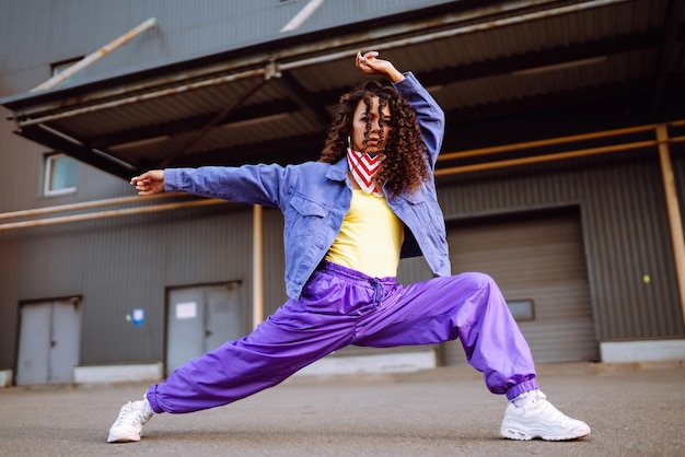 Jeune femme funky avec bandana américain dansant seule dans la rueDanse sportive et culture urbaine