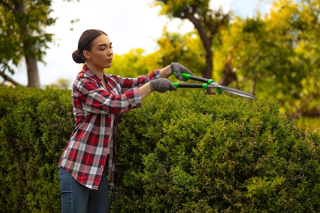 Jeune femme gadener coupant des branches sur l'arbre en prenant soin Concept de jardin passe-temps nature