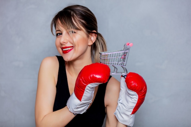 Jeune femme en gants de boxe avec panier sur fond gris. Style de lampe de poche des années 90