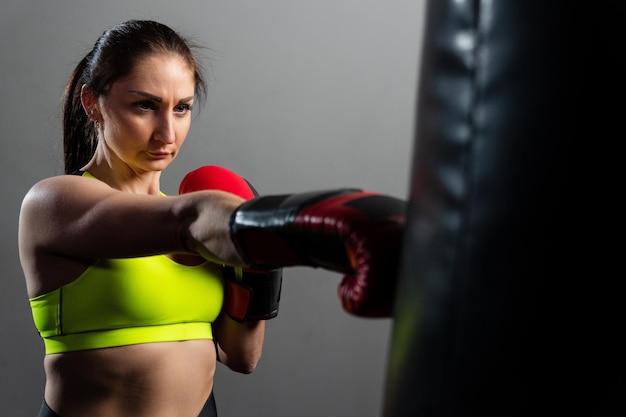 Une jeune femme en gants de boxe rouges s'entraîne dans la salle de sport