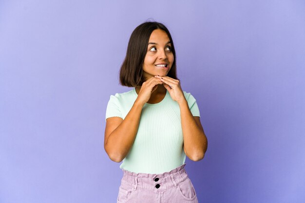 Jeune femme garde les mains sous le menton, regarde joyeusement de côté