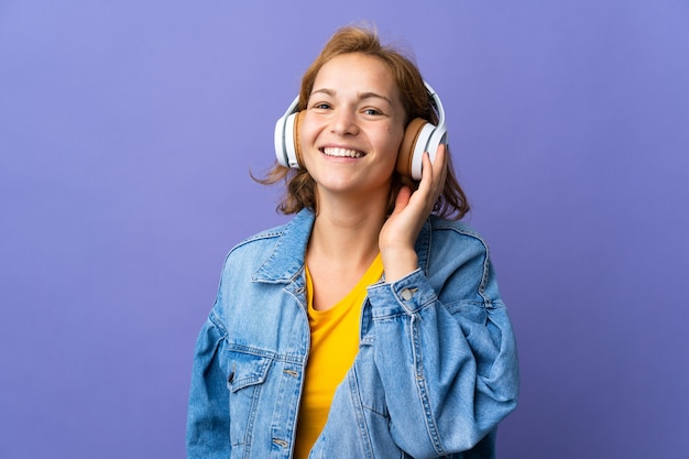 Jeune femme géorgienne isolée sur un mur violet à l'écoute de la musique