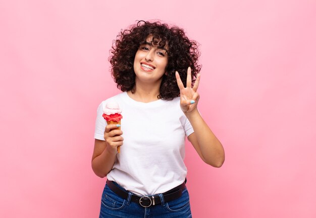 Jeune Femme Avec Une Glace Souriante Et Semblant Amicale, Montrant Le Numéro Trois Ou Troisième Avec La Main En Avant, Compte à Rebours