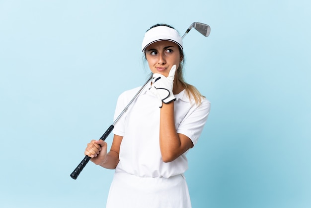 Jeune femme golfeuse hispanique sur mur bleu isolé ayant des doutes