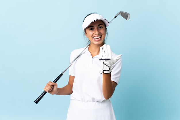 Jeune femme golfeuse hispanique sur mur bleu isolé invitant à venir avec la main. Heureux que tu sois venu