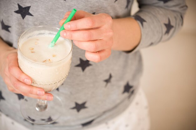 Jeune femme avec un grand verre de smoothie sain servi avec une paille et de l'avoine