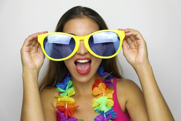 Photo jeune femme avec de grandes lunettes de soleil drôles et guirlande de carnaval sourire à la caméra