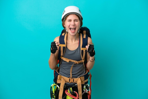 Jeune femme grimpeuse anglaise isolée sur fond bleu célébrant une victoire en position de gagnant