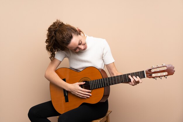 Jeune femme avec guitare sur mur isolé