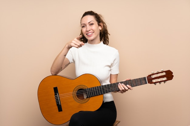 Jeune femme avec guitare sur points isolés doigt avec une expression confiante