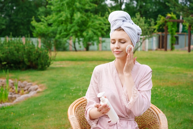 Jeune femme habillée pour la tête enveloppée de serviette de douche pour tenir les cheveux dans des bouteilles