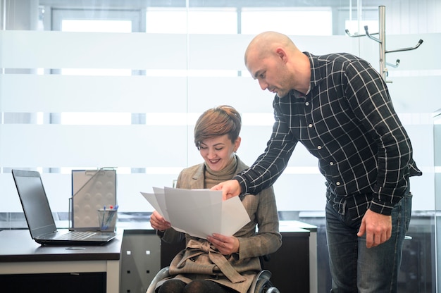 Photo jeune femme handicapée au bureau en regardant les papiers