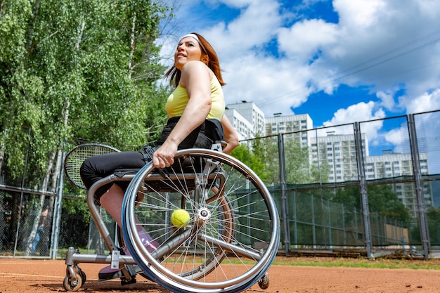Jeune femme handicapée en fauteuil roulant jouant au tennis sur un court de tennis
