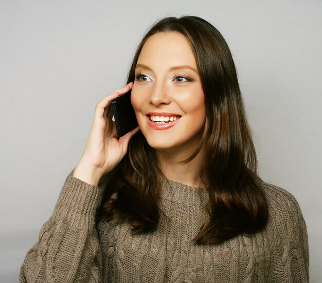 Jeune femme heureuse à l'aide d'un téléphone mobile isolé sur fond blanc