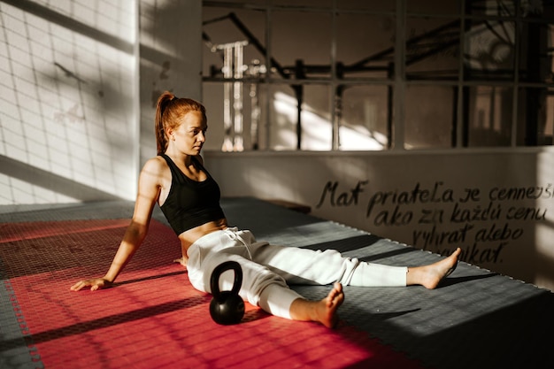 Une jeune femme heureuse après un entraînement de force assise sur le sol, une femme pleine d'endorphines.