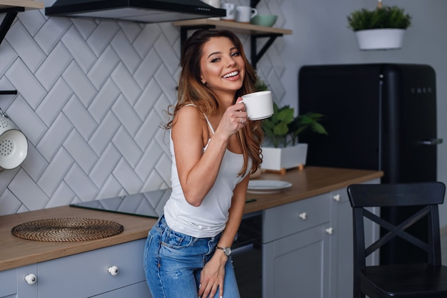 Jeune femme heureuse, boire du café dans la cuisine le matin