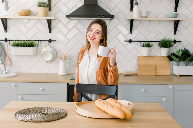 Jeune femme heureuse, boire du café dans la cuisine le matin.