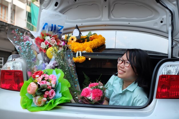 Photo une jeune femme heureuse avec des bouquets dans le coffre de la voiture.