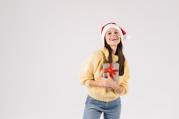 Photo jeune femme heureuse en chapeau de père noël regardant la caméra montrant un cadeau isolé sur un fond blanc