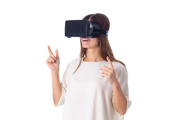 Jeune femme heureuse en chemise blanche à l'aide de lunettes de réalité virtuelle sur fond blanc en studio