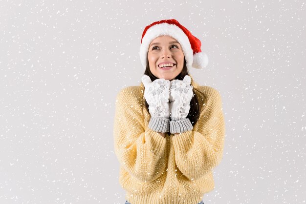 Photo une jeune femme heureuse dans un pull tricoté jaune et des mitaines blanches soufflant des flocons de neige