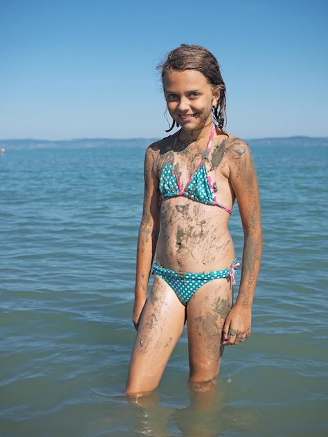 Photo une jeune femme heureuse debout dans la mer contre un ciel clair.