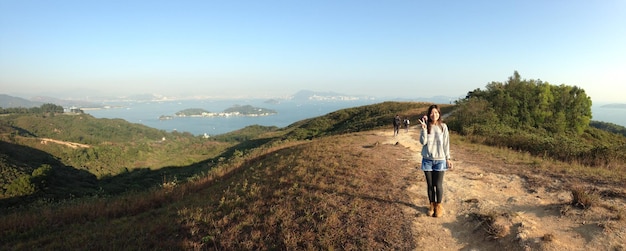 Photo une jeune femme heureuse debout sur une route de montagne contre un ciel clair