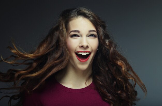 Jeune femme heureuse avec du vent dans les cheveux. Prise de vue en studio.