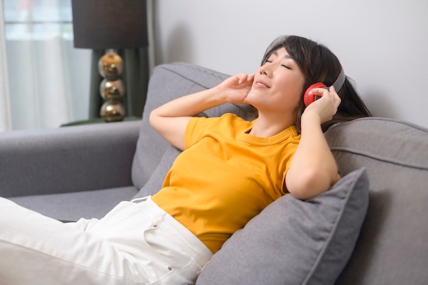 Une jeune femme heureuse écoutant de la musique et se relaxant à la maison