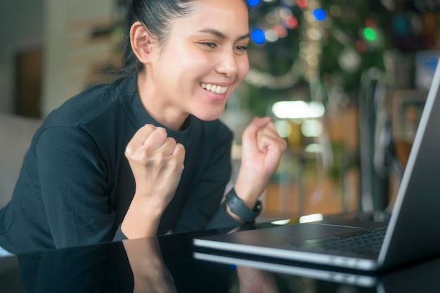 Une jeune femme heureuse est surprenante en utilisant un ordinateur portable dans un café et un concept technologique