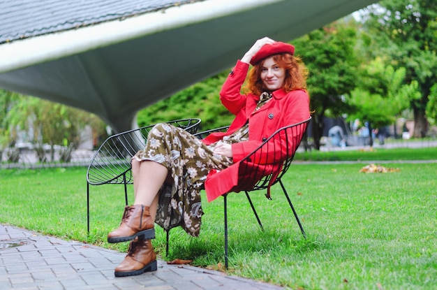 Jeune femme heureuse, étudiante aux cheveux roux, taches de rousseur, yeux bleus dans un béret, manteau marchant. parc d'automne