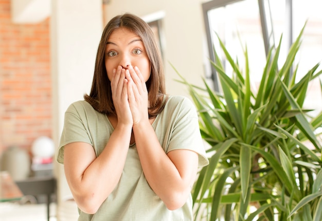 Jeune femme heureuse et excitée surpris et étonné couvrant la bouche avec les mains en riant avec une expression mignonne