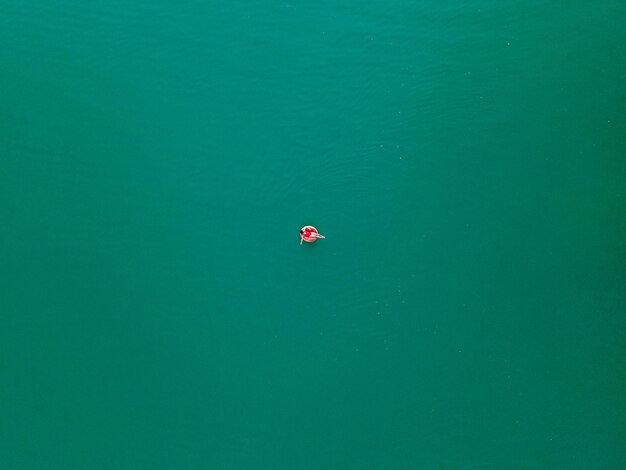 Jeune femme heureuse flottant dans l'eau bleu azur sur les vacances d'été de cercle d'anneau gonflable