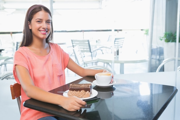 Jeune femme heureuse avec un gâteau et café