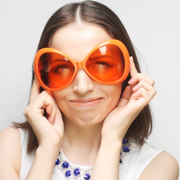 Jeune femme heureuse avec de grandes lunettes de soleil orange, prête pour la fête