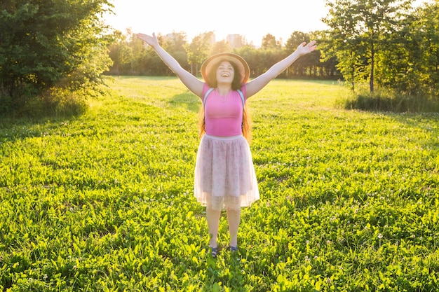 Jeune femme heureuse gratuite levant les bras en regardant le soleil en arrière-plan au lever du soleil.