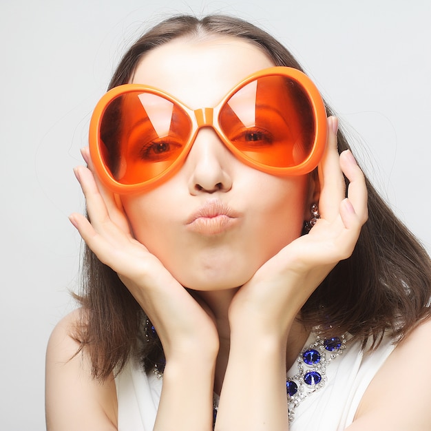 Jeune femme heureuse avec de grosses lunettes de soleil orange