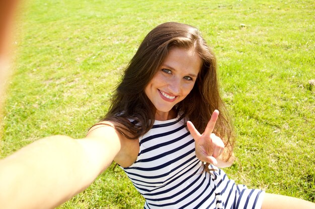 Photo jeune femme heureuse sur l'herbe prenant selfie